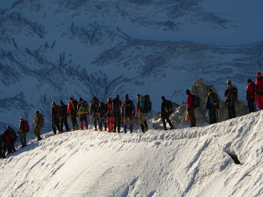 Group of climbers trekking on a snow-covered mountain, showcasing teamwork and adventure.