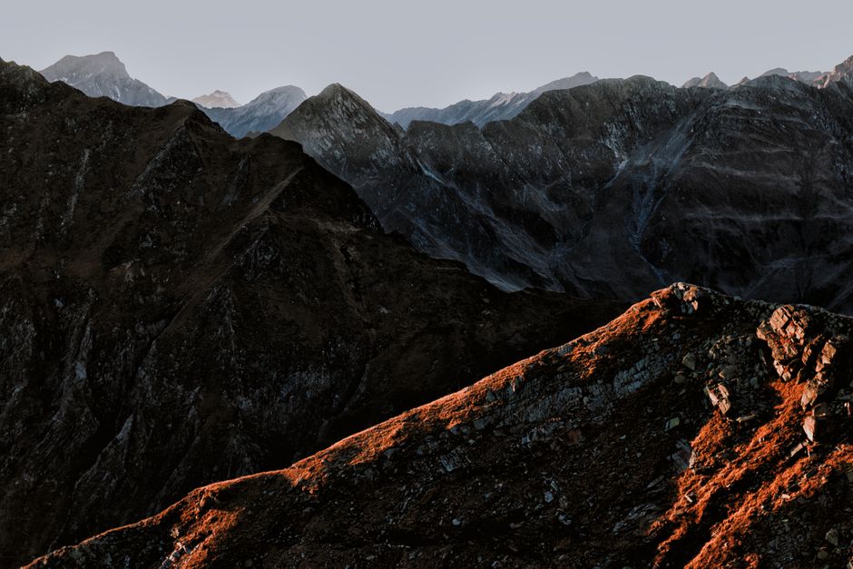 Stunning view of a mountain range at sunset with dramatic lighting and rocky terrain.