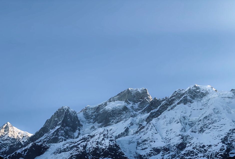 Breathtaking view of snow-covered mountains with clear blue sky backdrop, showcasing nature's beauty.